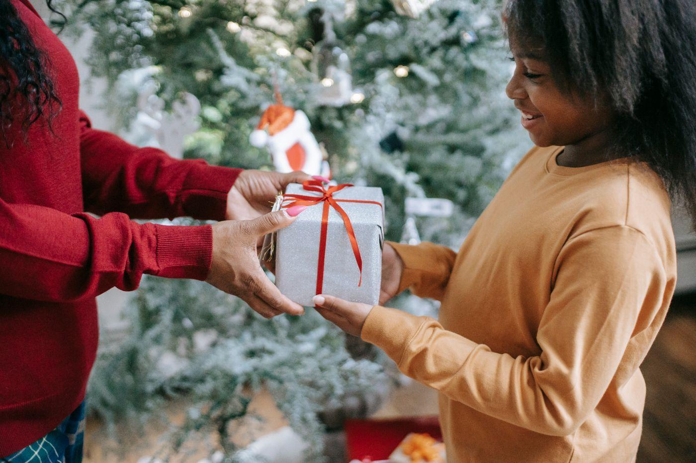 Une mère tend un cadeau à sa fille souriante
