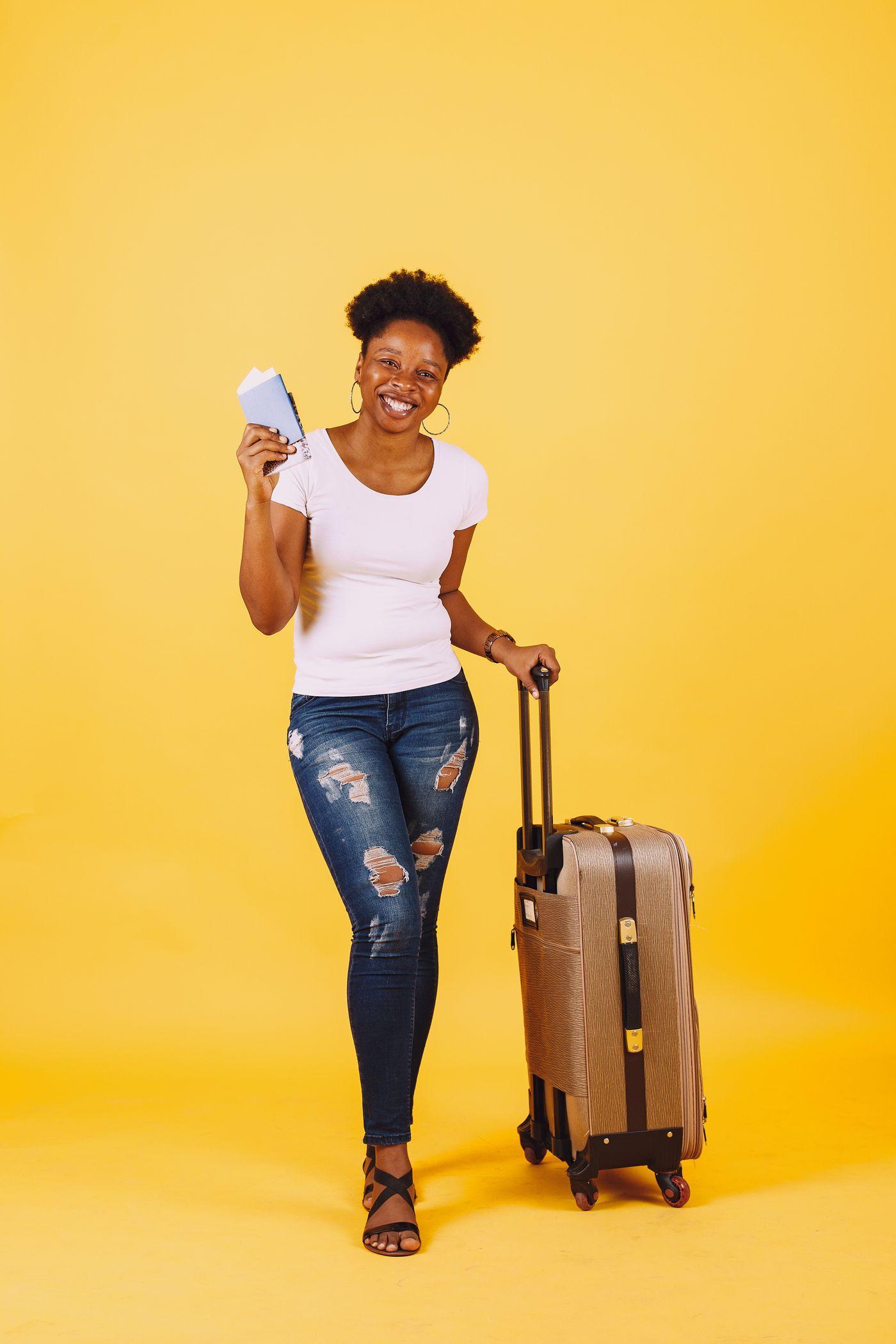 Une voyageuse souriante, billet en main, tire sa valise